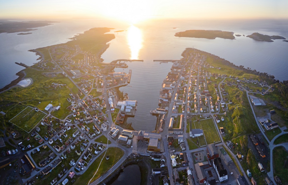 Vardø sett fra lufta i midnattssol, med havna og moloene